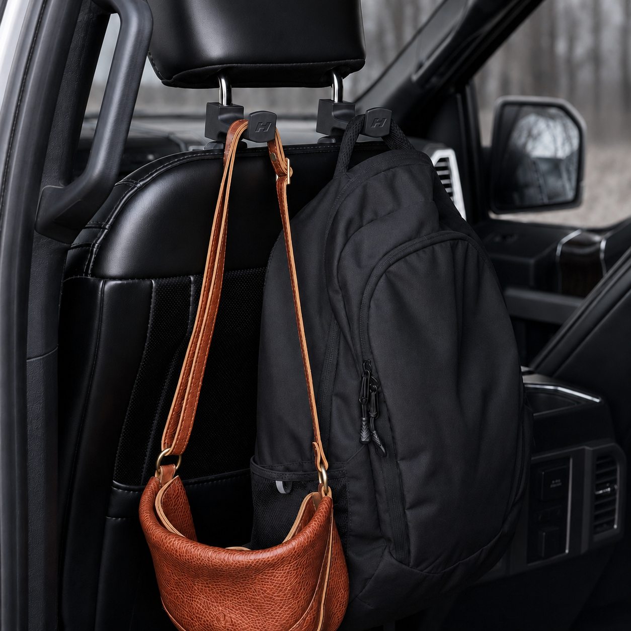 Car interior with a brown handbag and black backpack hanging from a hook on the back of the front seat.