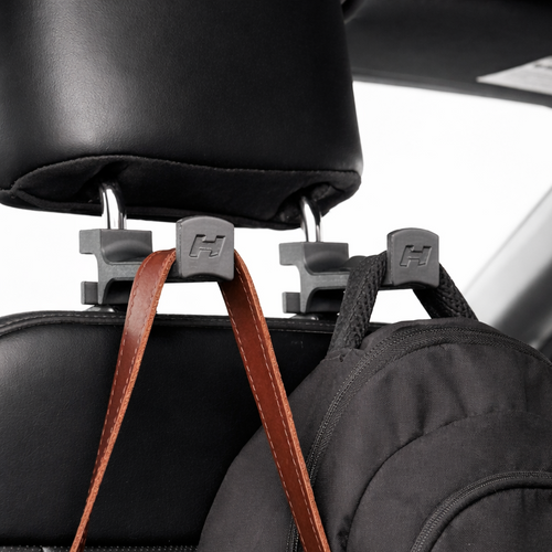 Car seat headrest hook holding a black backpack with brown straps.